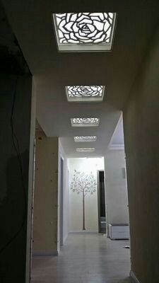 an empty hallway with white walls and ceiling lights on either side of the corridor, leading to another room