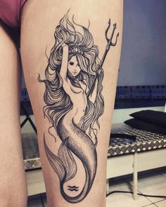 a woman's leg with a mermaid tattoo on it and an anchor in the middle