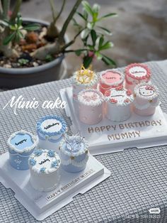 a table topped with lots of cupcakes on top of white plates next to a potted plant