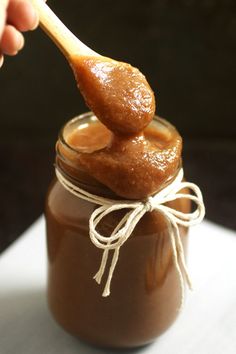 a spoon full of peanut butter on top of a jar