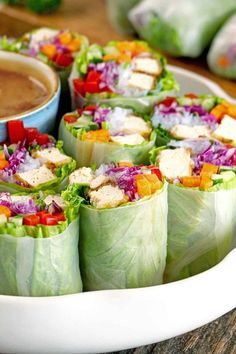 a plate filled with lettuce wraps next to a bowl of dipping sauce