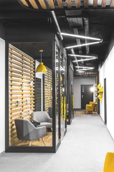 an office hallway with yellow chairs and wooden slats on the ceiling, along with white walls