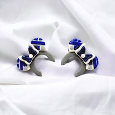 two blue and white earrings sitting on top of each other