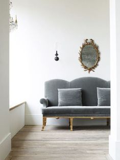 a couch sitting in front of a mirror on the wall next to a wooden floor