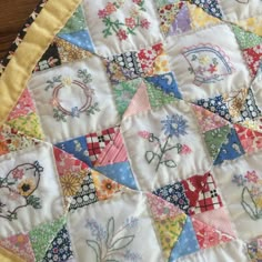 a close up of a quilted table topper on a wooden surface with flowers