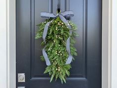 a wreath on the front door of a house with blue and white ribbons hanging from it