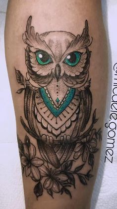 an owl with blue eyes and flowers on the leg is seen in this tattoo design