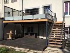 a house with a deck and stairs leading up to the second floor, next to an apartment building