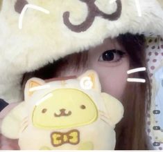 a woman holding a stuffed animal in front of her face and wearing a cat hat