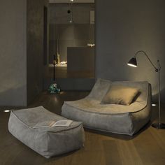 a living room filled with furniture and a book on top of a wooden floor next to a lamp