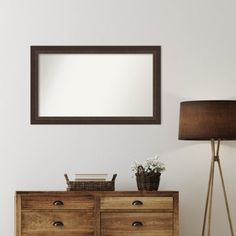 a wooden dresser sitting next to a lamp and mirror