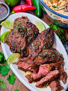 steak with lime wedges and cilantro garnish on a white plate