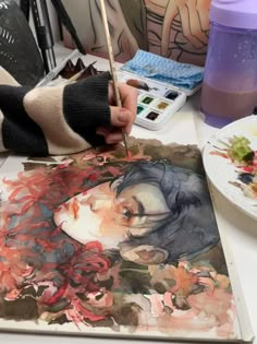 a person is painting on paper with watercolors