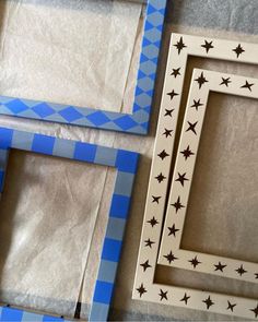 three wooden frames sitting next to each other on top of a table covered in blue and white paper