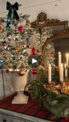 a decorated christmas tree in front of a mirror with lit candles and cookies on it