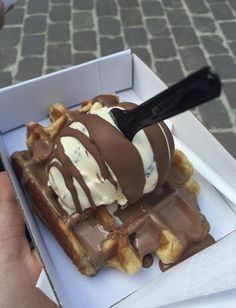 a waffle with ice cream and chocolate on top is in a white cardboard box