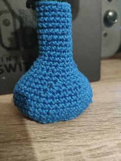 a crocheted blue vase sitting on top of a wooden table