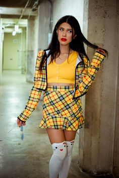 a woman with long hair wearing a yellow shirt and plaid skirt is posing for the camera