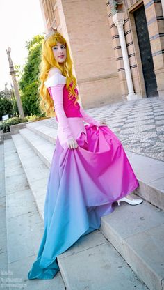 a woman in a pink and blue dress sitting on some steps