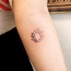 a small sun and leaf tattoo on the arm