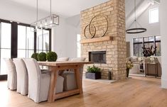 a dining room table with chairs and a fireplace in the middle of an open floor plan