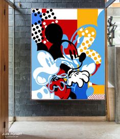 a mickey mouse painting hanging on a brick wall