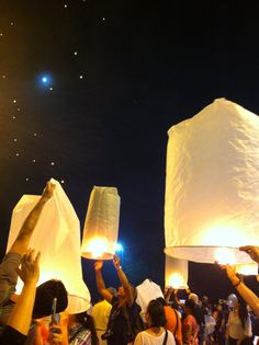 people holding up paper lanterns in the air