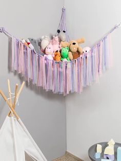 several stuffed animals are sitting in a toy hammock with streamers hanging from the ceiling