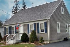 a gray house with blue shutters and a flag on the front