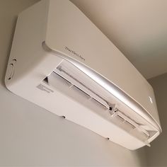 an air conditioner mounted on the side of a wall in a room with white walls