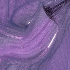 a purple brush is laying on top of some shiny material that looks like it has been dyed