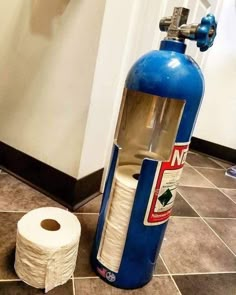 a blue fire extinguisher sitting on the floor next to a roll of toilet paper