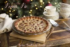 a pecan pie sitting on top of a wooden table next to a christmas tree