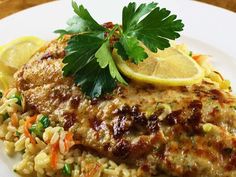 a white plate topped with meat and rice covered in lemon wedged garnish