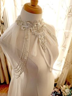 a mannequin wearing a white dress with beaded trims and pearls on it