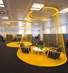 an office cubicle with two chairs and a table in the center, surrounded by yellow mesh