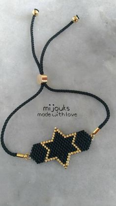 a black and gold beaded bracelet with an image of a star in the middle