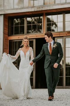 a bride and groom holding hands walking in front of a building