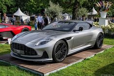 a silver sports car parked on top of a wooden platform in front of other cars