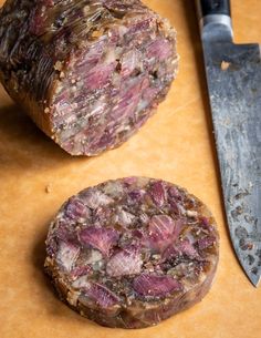 two pieces of meat sitting on top of a cutting board next to a knife