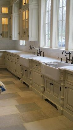 a kitchen filled with lots of white cabinets and counter top space next to two sinks