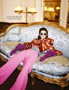 a woman laying on top of a couch in front of a mirror wearing pink pants