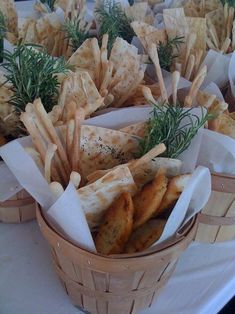 several baskets filled with different types of food on top of a white tablecloth covered table