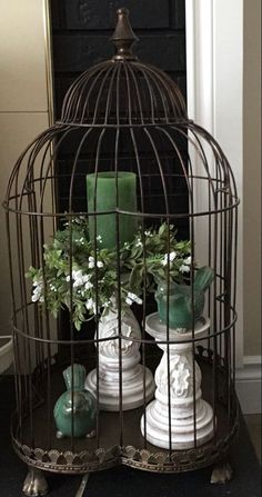 a birdcage with candles and flowers in it