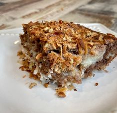 a piece of cake sitting on top of a white plate covered in nuts and other toppings