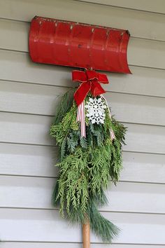 a red mailbox hanging from the side of a house with a wreath on it