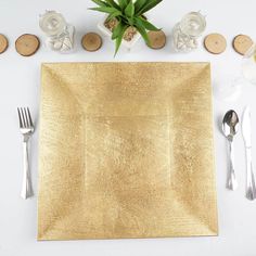 a place setting with silverware and succulents on the side, along with a gold napkin