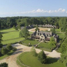 an aerial view of a large home surrounded by lush green trees and lots of grass