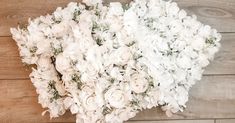 a bouquet of white flowers sitting on top of a wooden floor next to a wall