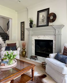 a living room filled with furniture and a fire place in front of a white fireplace